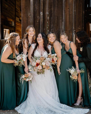 Bride in white dress posing with bridesmaids in green dresses