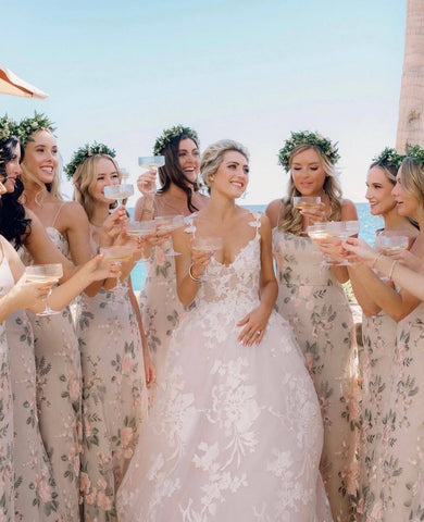 Bride in white dress standing with seven bridesmaids in pink floral dresses