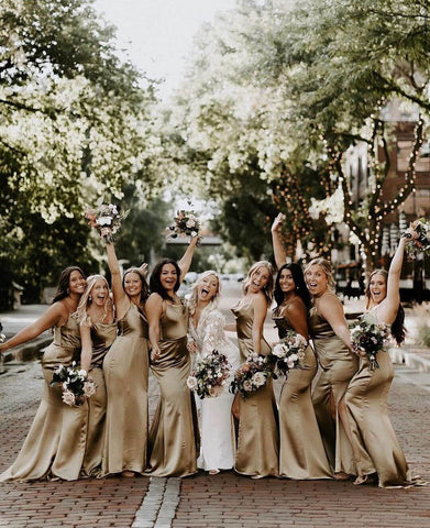 Bride in ivory dress posing with eight bridesmaids in gold dresses