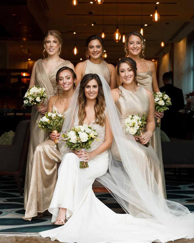 Bride in ivory dress posing with bridesmaids in gold dresses