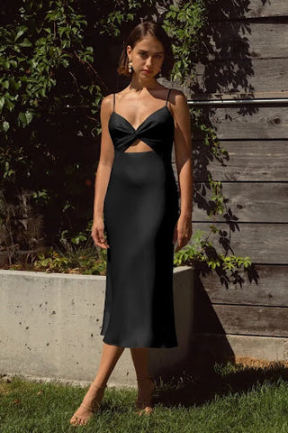 Model is wearing a slip style midi dress with a cut-out at waist and knot in the middle of the bust (v-neck).