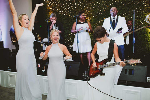 Bride playing guitar with bridesmaids dancing near her