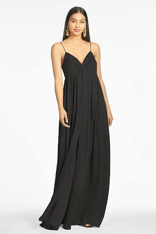 Model is wearing a full-length, flowing, black v-neck gown with an empire waist and