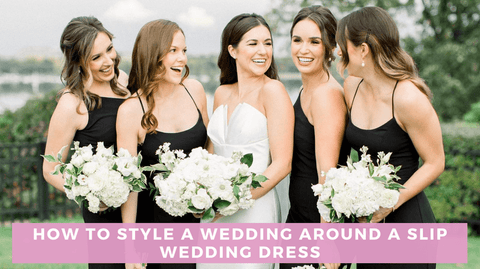 Bride in white slip wedding dress and four bridesmaids in black dresses