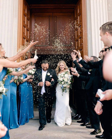 Bride and groom walking out of church with bridal party throwing rice at them