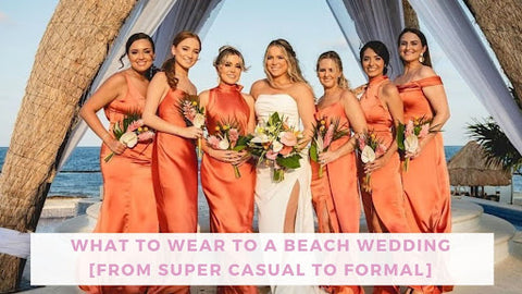 Bride in white strapless gown with split in skirt and her six bridesmaids in peach silk dresses of various styles in front of a beach.
