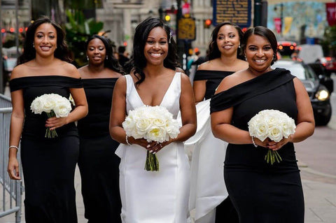 Bride in white dress with bridesmaids in black dresses