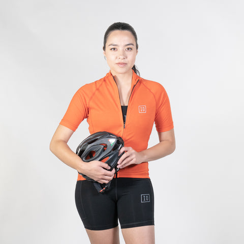 Model wearing ioMerino's Women's Cycling Jersey in Orange