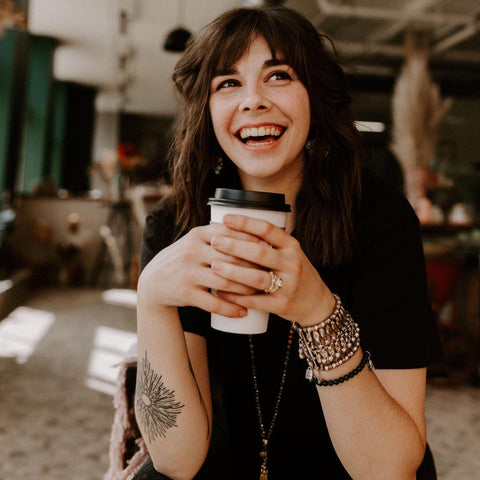 Kelly Robertson laughing and holding a to-go cup of coffee