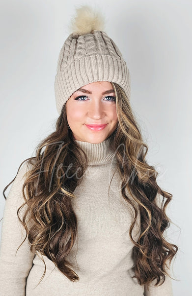 A woman wears a fleece hat with a faux fur pom pom - Fleece Chic