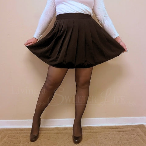 A twirly skirt with pleating is worn by a woman in black high heels and a long sleeve white shirt - Fleece Chic