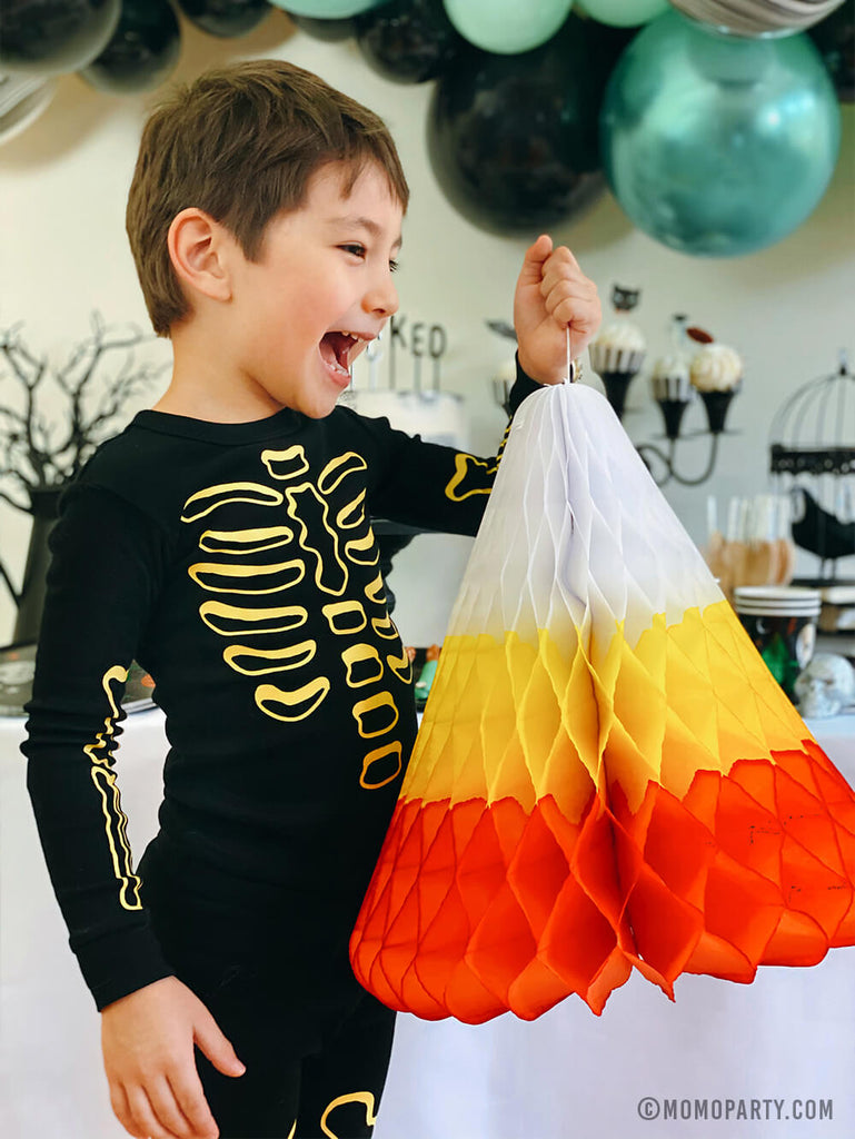 Kids Low-Contact Halloween Party Ideas by Momo Party - A boy holding candy corn decoration in a Halloween party at home