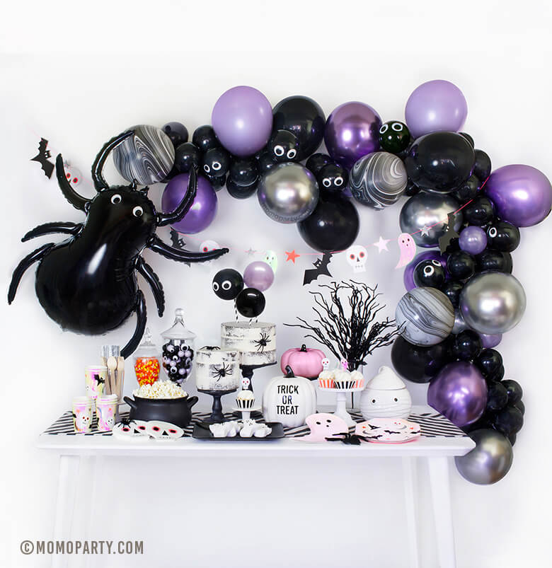 Momo Party Halloween Box look with spider balloon, chrome purple, pearl purple, black and chrome silver mixed latex balloon garland, table set up with ghost plates, halloween icon plates and cups, pink pumpkin decorations