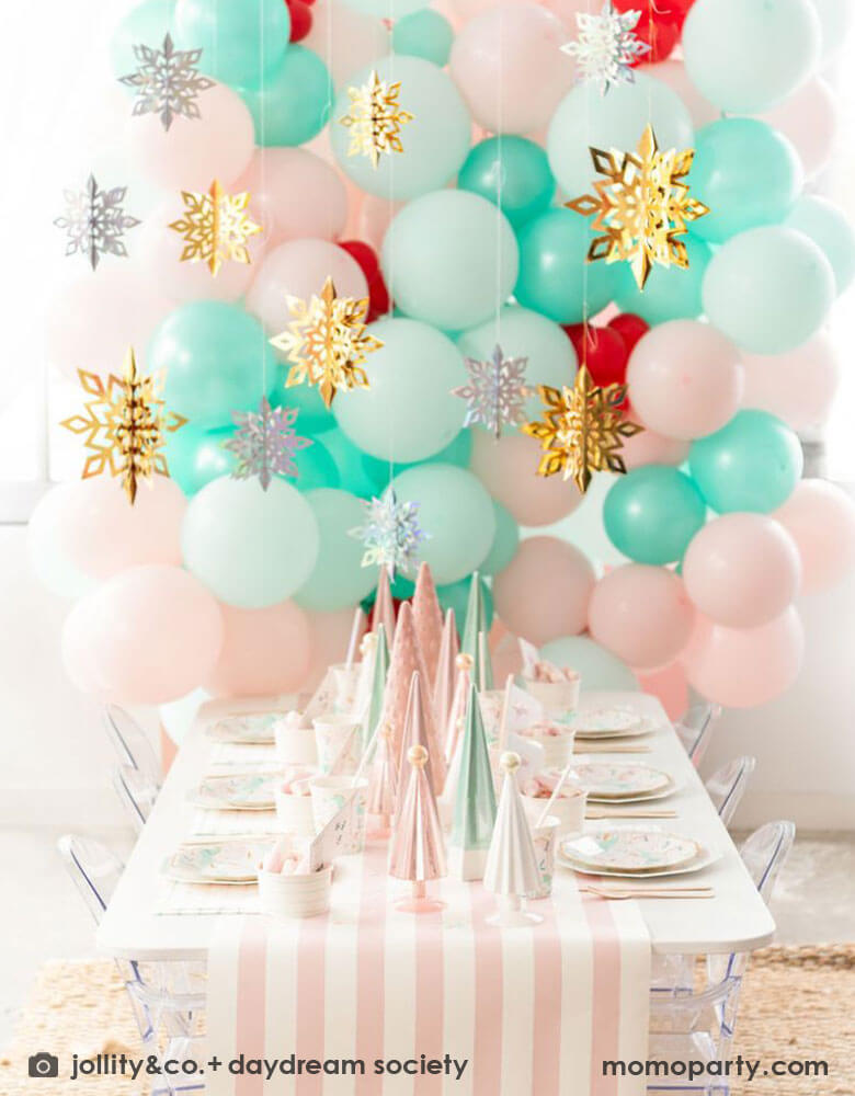 Winter Wonderland Themed First Birthday Party Decoration featuring a pastel balloon wall adorned with silver and gold snowflake hanging decorations.