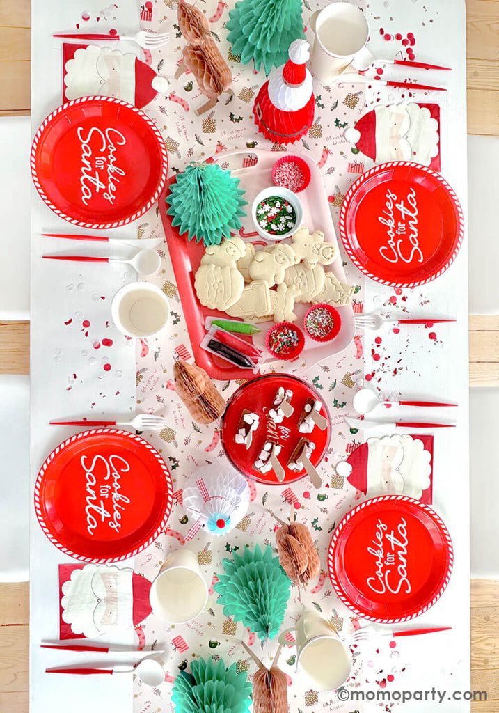 A festive Holiday party table featuring Momo Party's Cookies for Santa red round plates, Santa shaped napkins, Santa head shaped party cups, red and white reusable cutlery set. In the middle Holiday character honeycombs are used as centerpiece including Santa, reindeers, snowman and Christmas trees, all creates a holly jolly holiday table set for a fun gathering for kids.