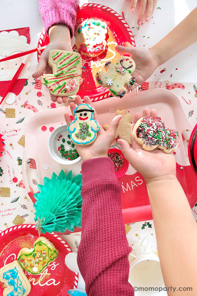 Kids showing off their decorated cookies from a festive Kid's Christmas Cookie Decorating Party by Momo Party.