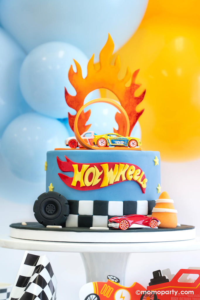 Hot Wheels themed birthday cake with the classic orange curve track and Hot Wheels toy cars. On the side of the cake are a fondant wheel and construction cone, making this a perfect look for kid's Hot Wheels themed birthday party.