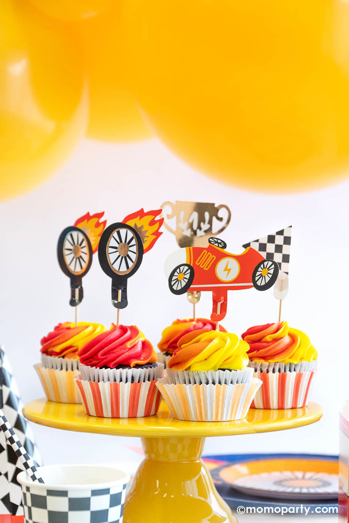 Hot Wheels themed cupcakes with yellow and orange flame swirl topped with Momo Party's car cupcake toppers featuring a trophy, a checker flag, a wheel and a vintage race car.