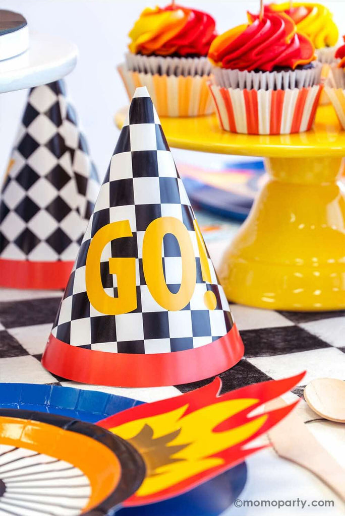 Kid's Hot Wheels themed birthday party table features Momo Party's midnight dinner plates, wheel shaped plates and checkered Go! birthday hats on a checkered table runner.