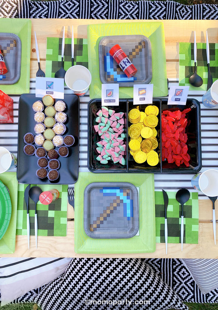 Creative Minecraft themed Birthday Party Sweets and Party Snacks Ideas by Momo Party. Including mini carrots, chocolate coins for Minecraft coin, Swedish fish, melon slice gummies, pretzel sticks, and Twizzlers to make TNTs, Jello for Water. Brazilian bite-size chocolate sweets for spaw eggs and sword. surrounding with Minecraft Twist Poppers layered on top of Minecraft themed party plates, pixel TNT theme goodie bags decorated the kids picnic table. 