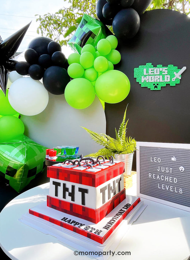 Minecraft themed Birthday Party Ideas by Momo Party. Featuring a TNT cake, a letter board with "Leo just reached level 8" text, and jello and tnt treats in a black cake stand,  in front of the backdrop black board with 3D Minecraft-inspired wall sign with "Leo's world"