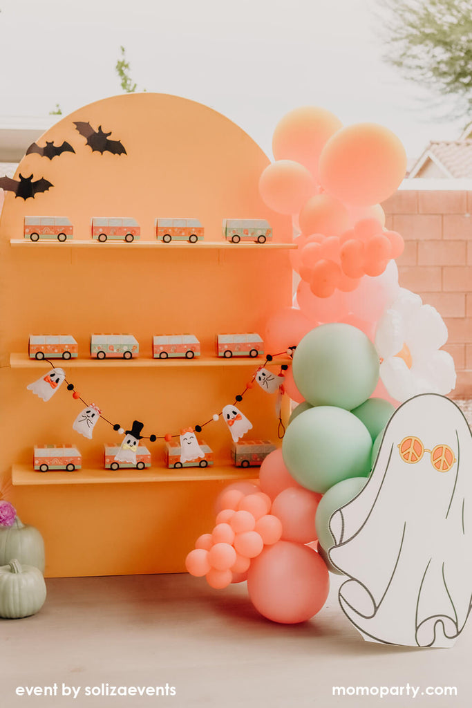 Momo Party & Soliza Events Groovy Halloween Party Favor Wall decorated with pastel balloon garland with a ghost with daisy shaped sunglasses board next to it. Makes it a perfect inspo for kid's Halloween party decoration.