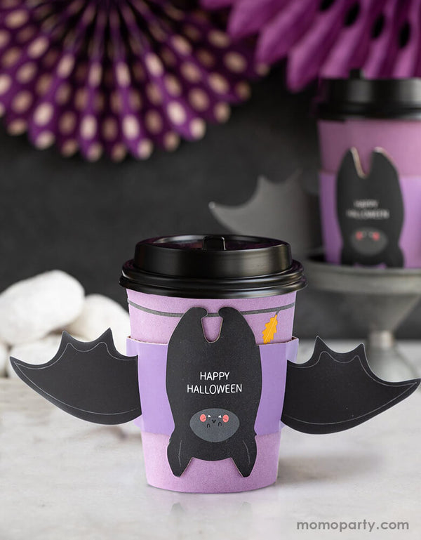 My Mind's Eye BAT HUGS TO-GO COZY CUPS. 8 oz coffee cups with sleeves and lids, this halloween To-Go Cozy Cups featuring a bat with wing sleeve in a purple print cup with "happy halloween" text print on the bat belly, super fun coffee cups for halloween season