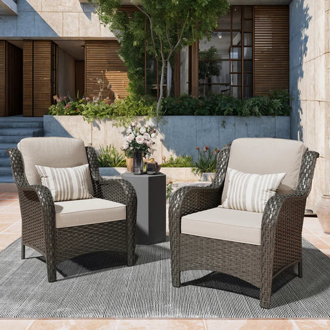 Two stylish outdoor armchairs, crafted from dark brown wicker and featuring plush beige cushions, are positioned on a textured gray rug.