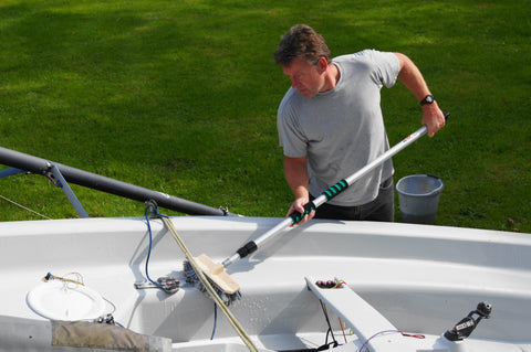 man scrubbing inside boat with long brush