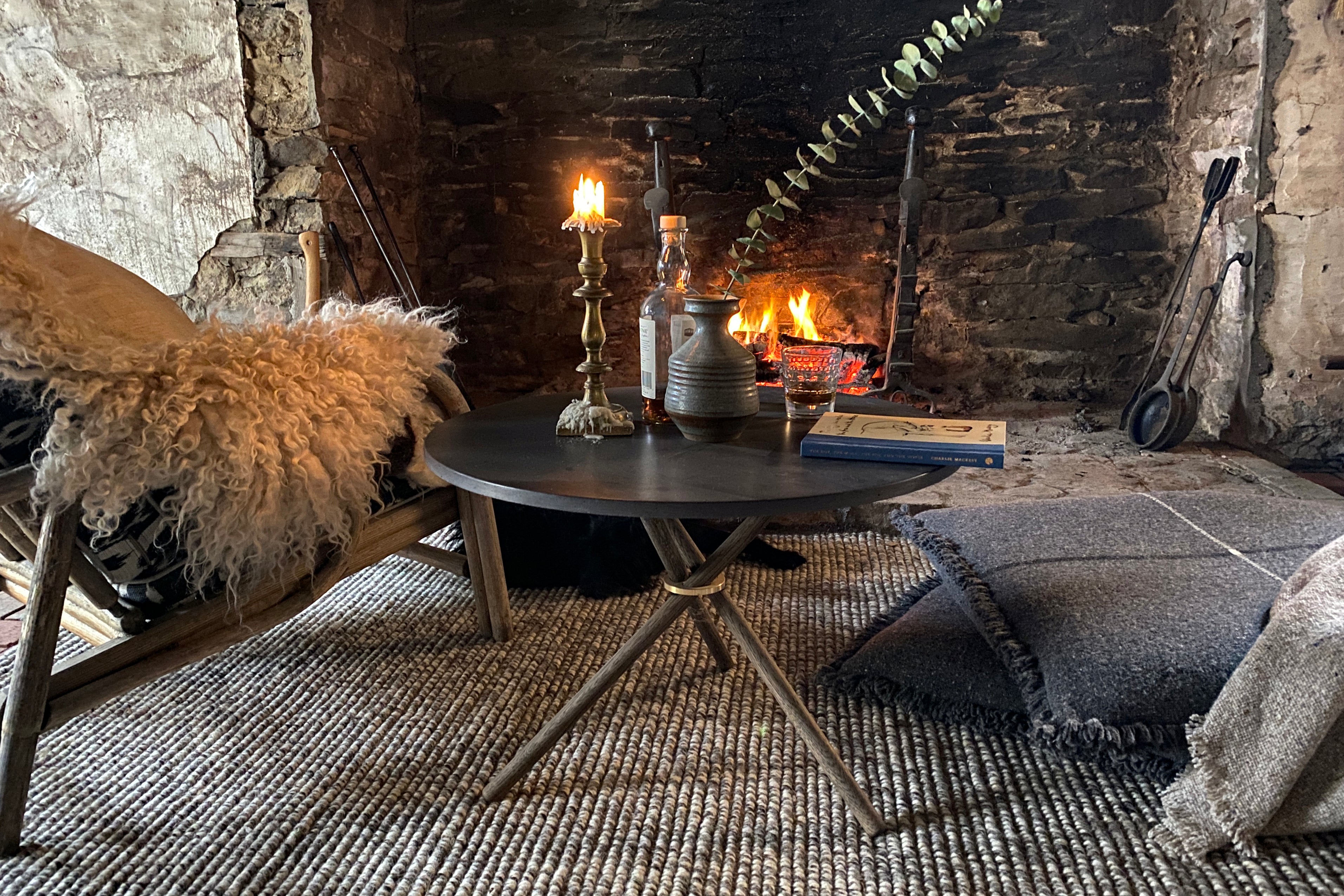 Charcoal wool floor pillows stacked by a fireplace.