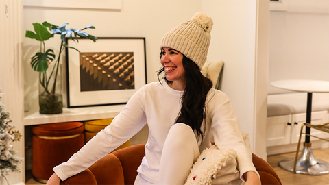 Woman wearing Heat Holders® base layers and hat smiles while sitting.
