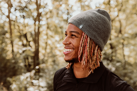 Man wearing a Heat Holders® beanie stands smiling in the woods