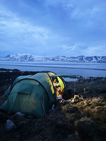 People tent camping in a cold, snowy location. | Heat Holders® for warmth when cold campiing or hiking.