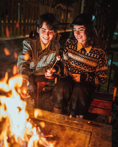 Two people roast marshmallows on an open fire. | Merino socks | Heat Holders®