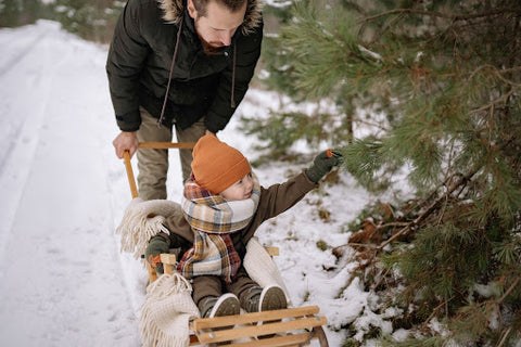 Dad pushing son on wooden toboggan in the snow