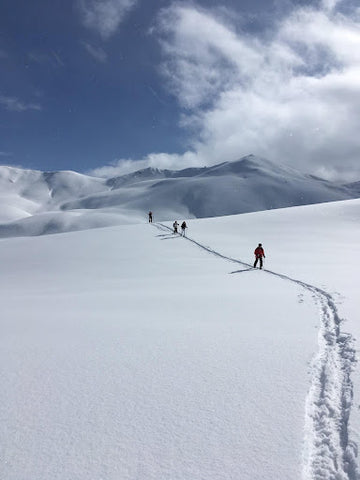 A group of hikers work they way across a snowy slope | Heat Holders® hats, beanies