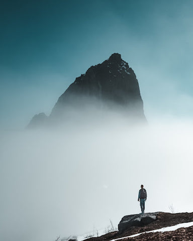 Man standing in front of a foggy mountain peak