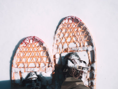 A person looking down at snowshoes they are wearing.