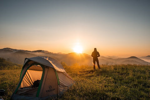 Man watches sun go down near his tent while cold camping. Heat Holders®