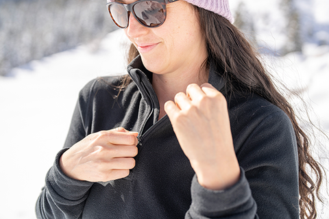 Woman zips up her thermal midlayer. | Heat Holders®