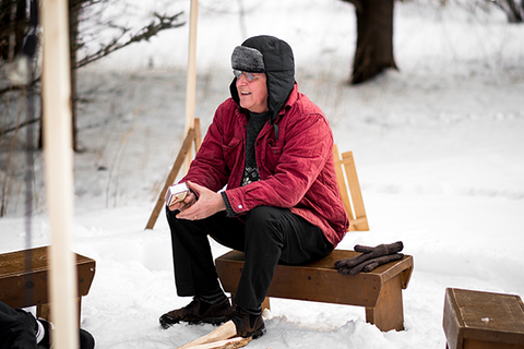Older man sits by the fire in the winter. | Heat Holders®