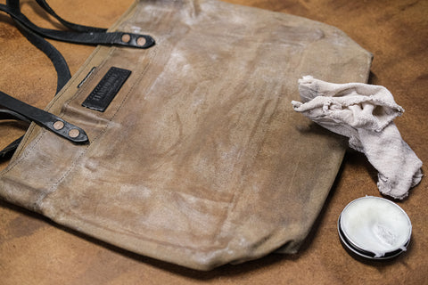 waxed canvas tote covered in wax next to a rag and tin of wax