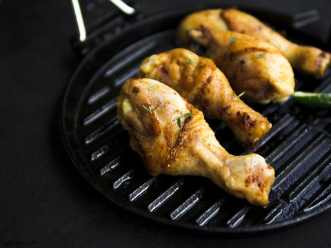 A close-up of air fryer chicken on a dark pan.