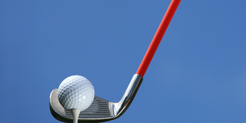 Golf Ball on Tee with Golf Iron and Red Shaft Behind