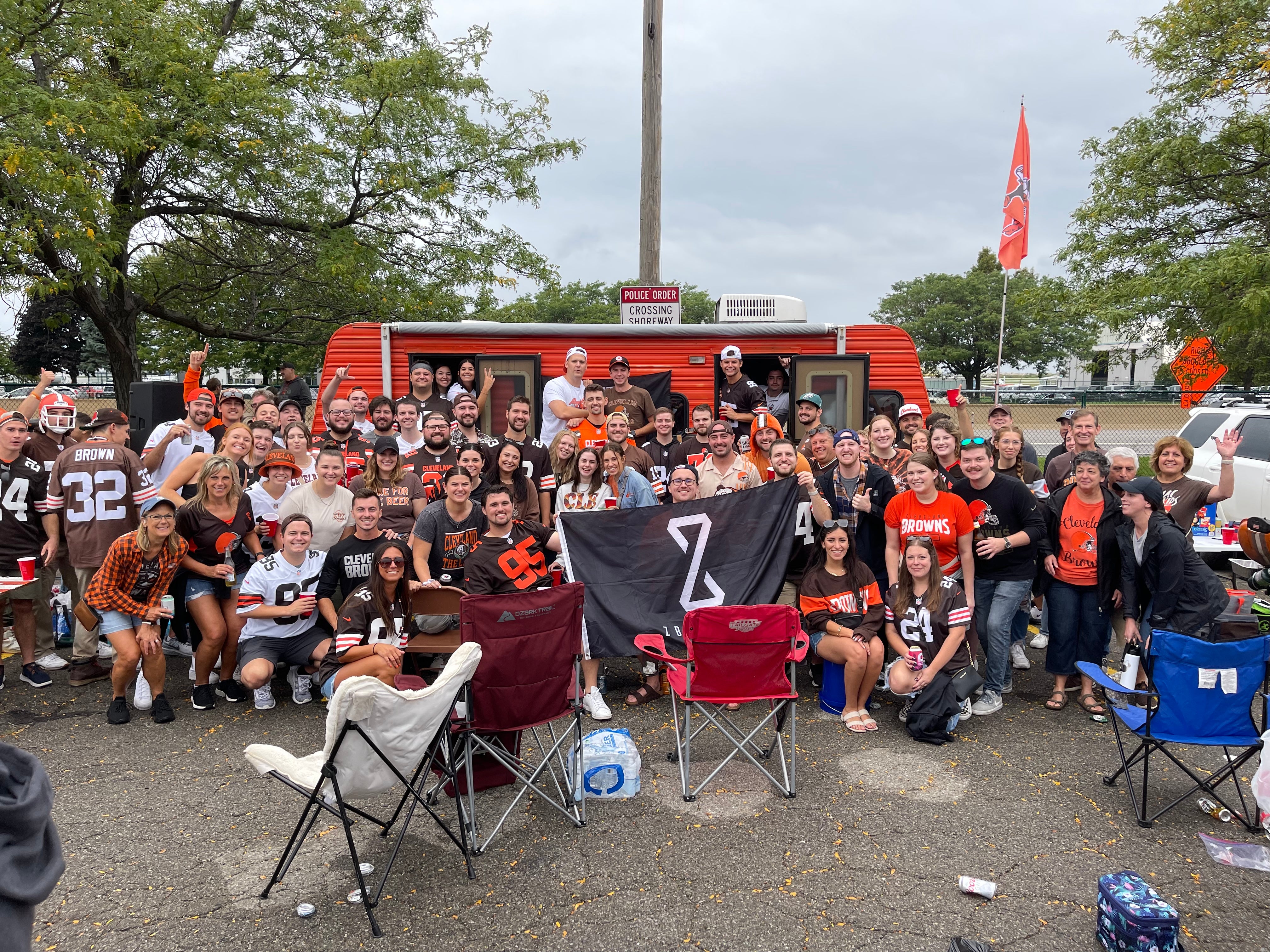 Sports fans holding a ZBiotics flag at a tailgate.