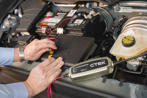 hands hooking a CTEK battery charger to a car battery