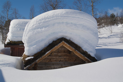 Cottage covered with lots of white snow on the roof