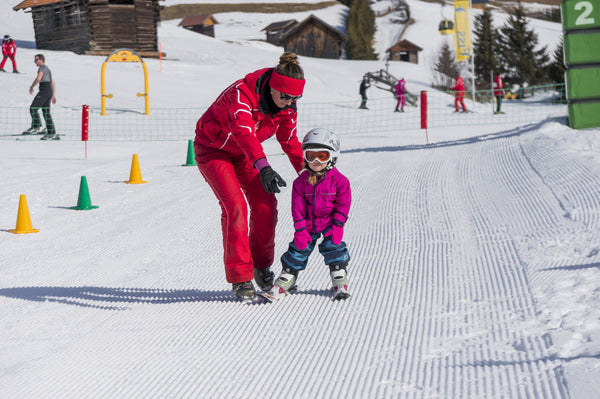 a mother teaching her daughter to ski