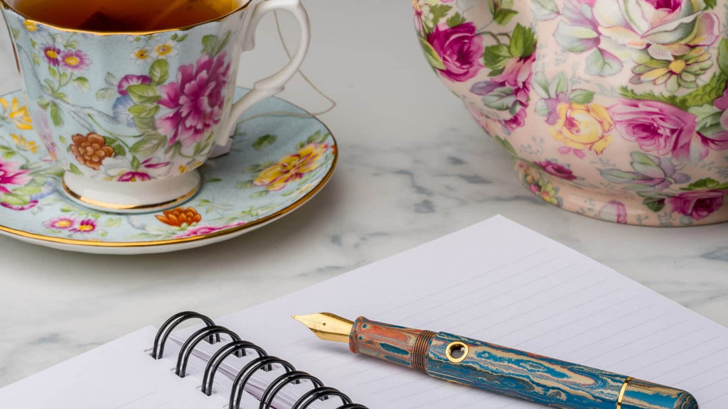 A Harmony of Opposites: EndlessPens Celebrates National Poets Day - A Teacup And Saucer Next To A Notebook And A Pen | EndlessPens