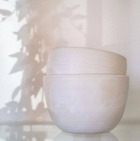 Two white ceramic ramen bowls sitting on the counter, stacked on top of each other.